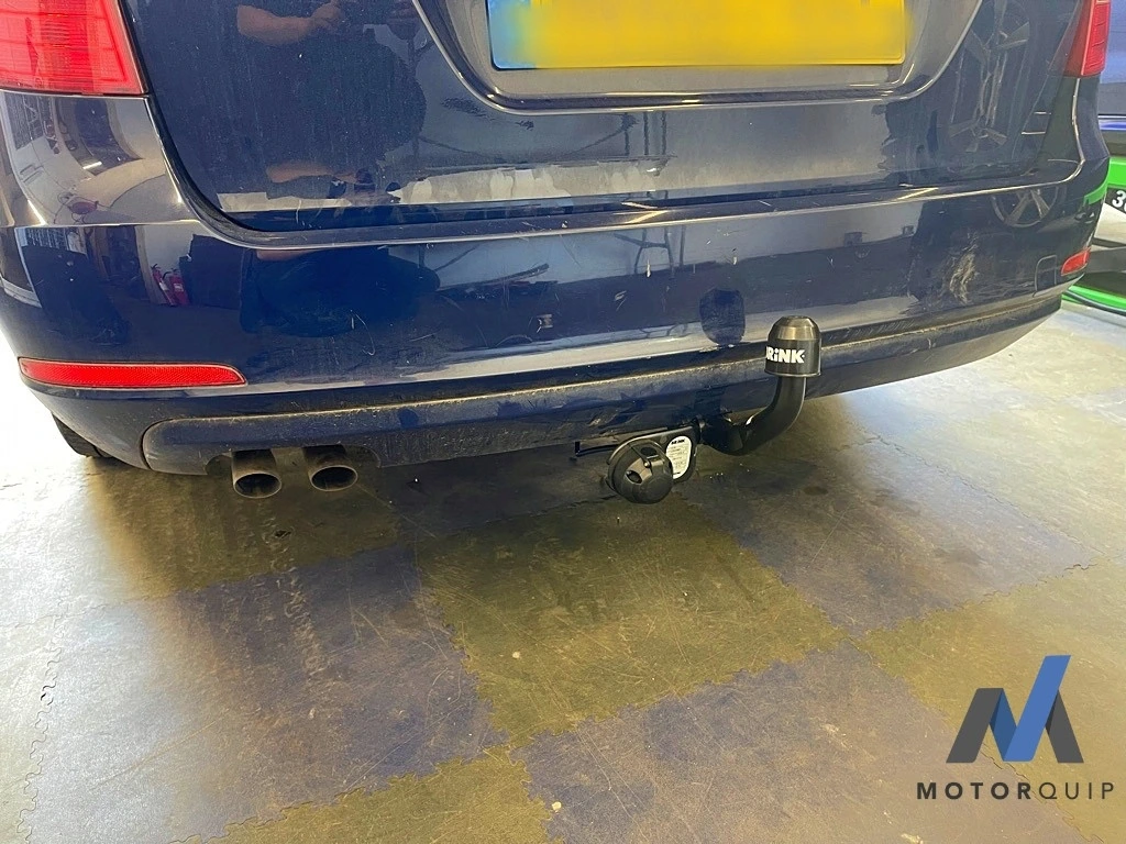 Rear view of a dark estate car with its fitted towbar in the workshop