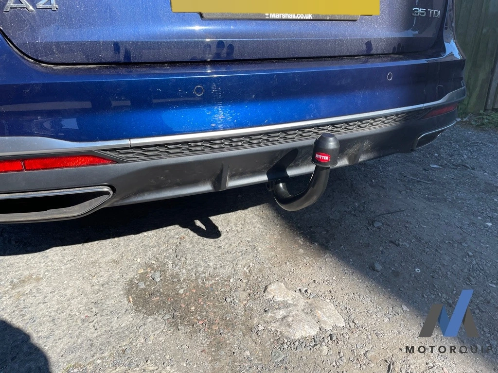 Towbar and electrical socket fitted beneath a blue vehicle’s rear bumper