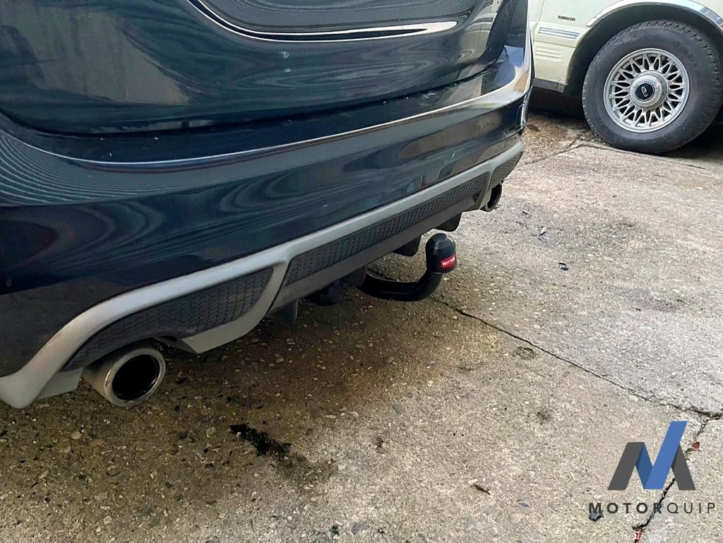Towbar fitted beneath the rear bumper of a dark Volvo